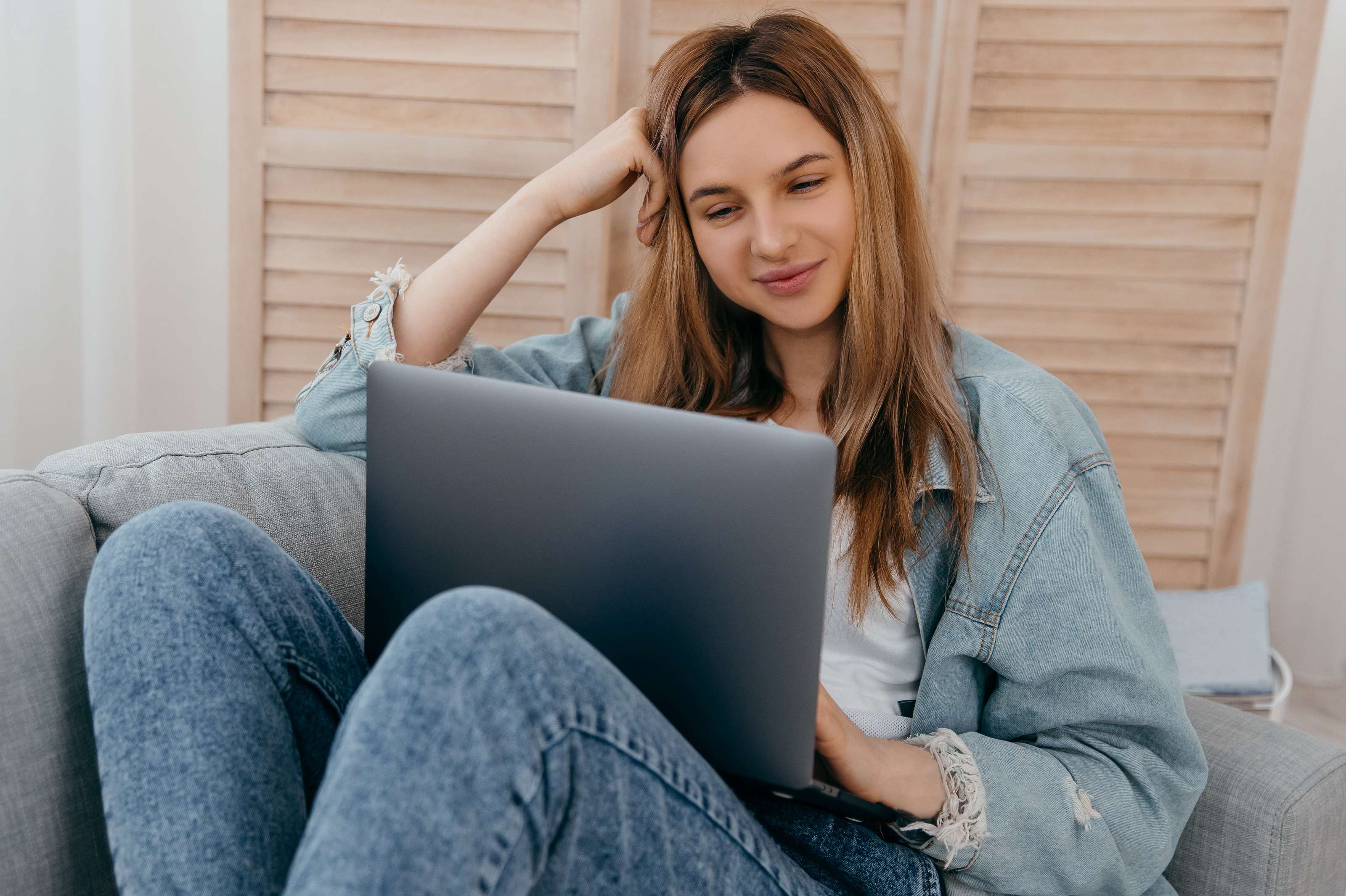 Allianz Gesundheitswelt - Allianz Gesundheits Talks: eine junge Frau mit langen Haaren und  Jeanshemd sitzt auf einer Couch und hat ihren Laptop auf dem Schoß.