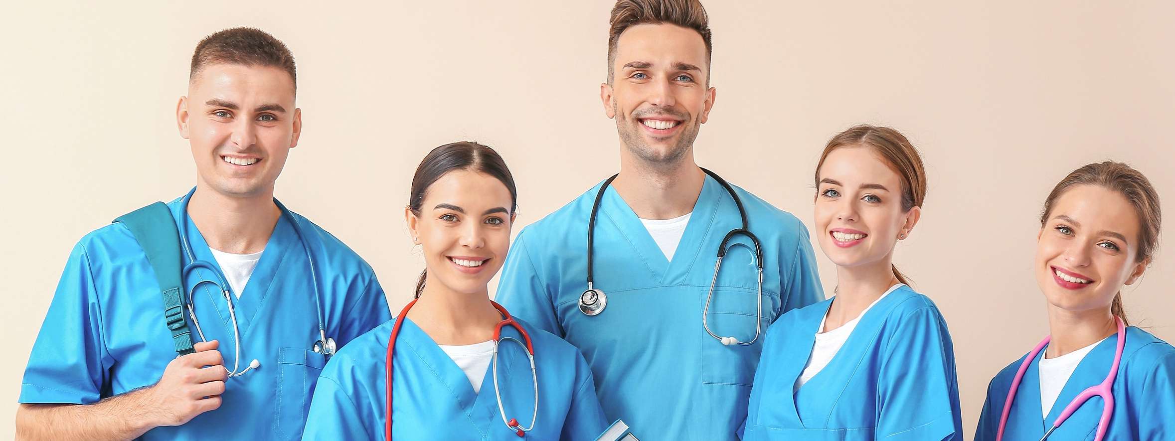 Allianz betriebliche Krankenversicherung Angebot für Beschäftigte im Gesundheitswesen: eine Gruppe junger Menschen in blauen Arztkitteln mit Stethoskopen um den Hals lächelt in die Kamera