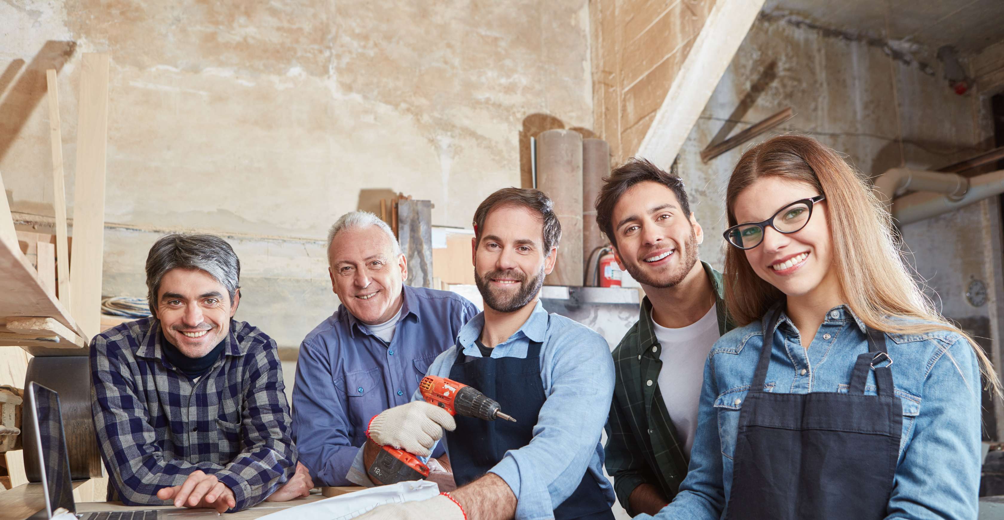 Allianz betriebliche Krankenversicherung: eine Gruppe von Menschen mit Arbeitskitteln steht vor einem Zeichenplan und lächelt in die Kamera.