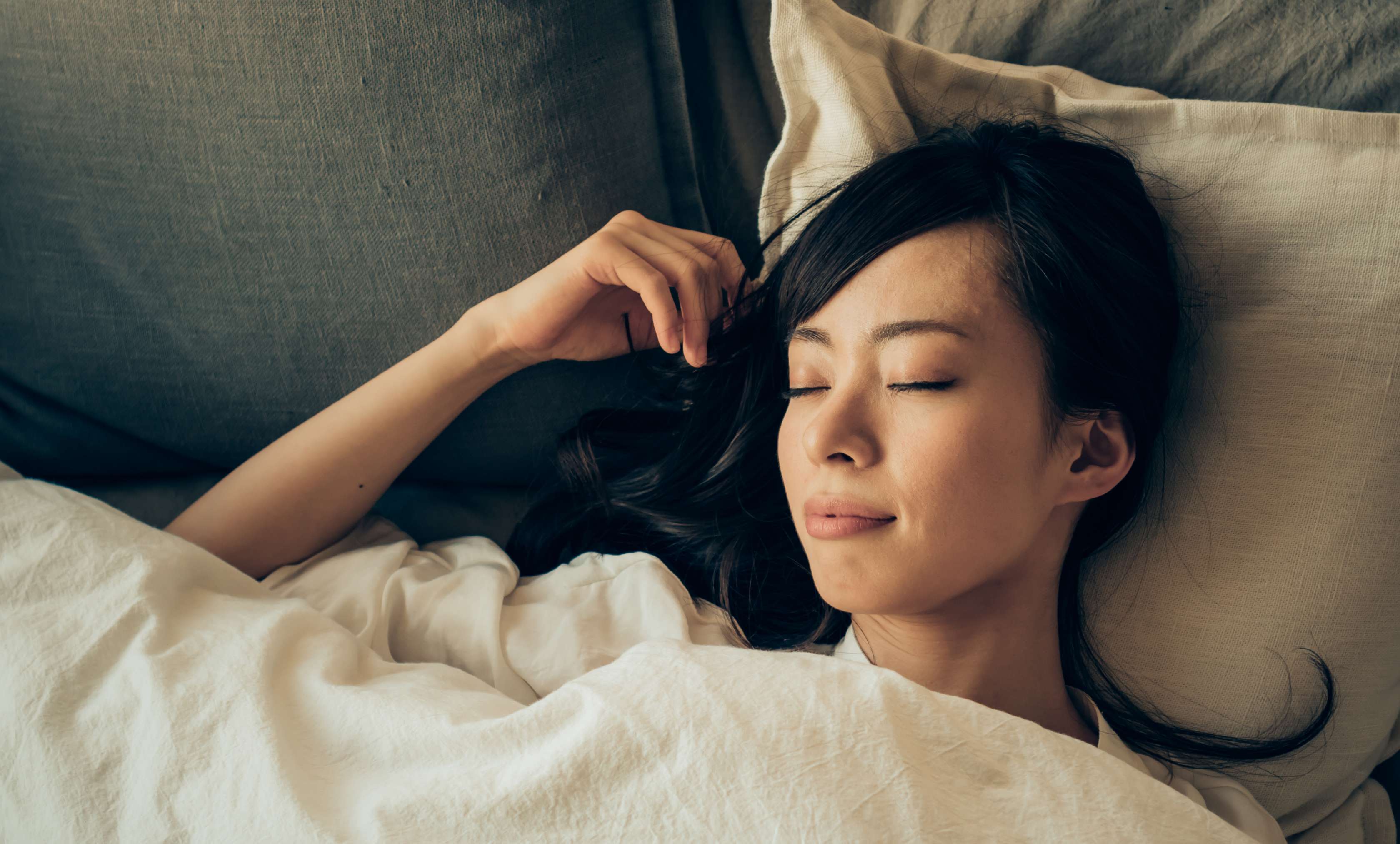 Allianz Gesundheitswelt - Gesunder Schlaf für Berüfstätige: eine asiatische Frau liegt schlafend im Bett.