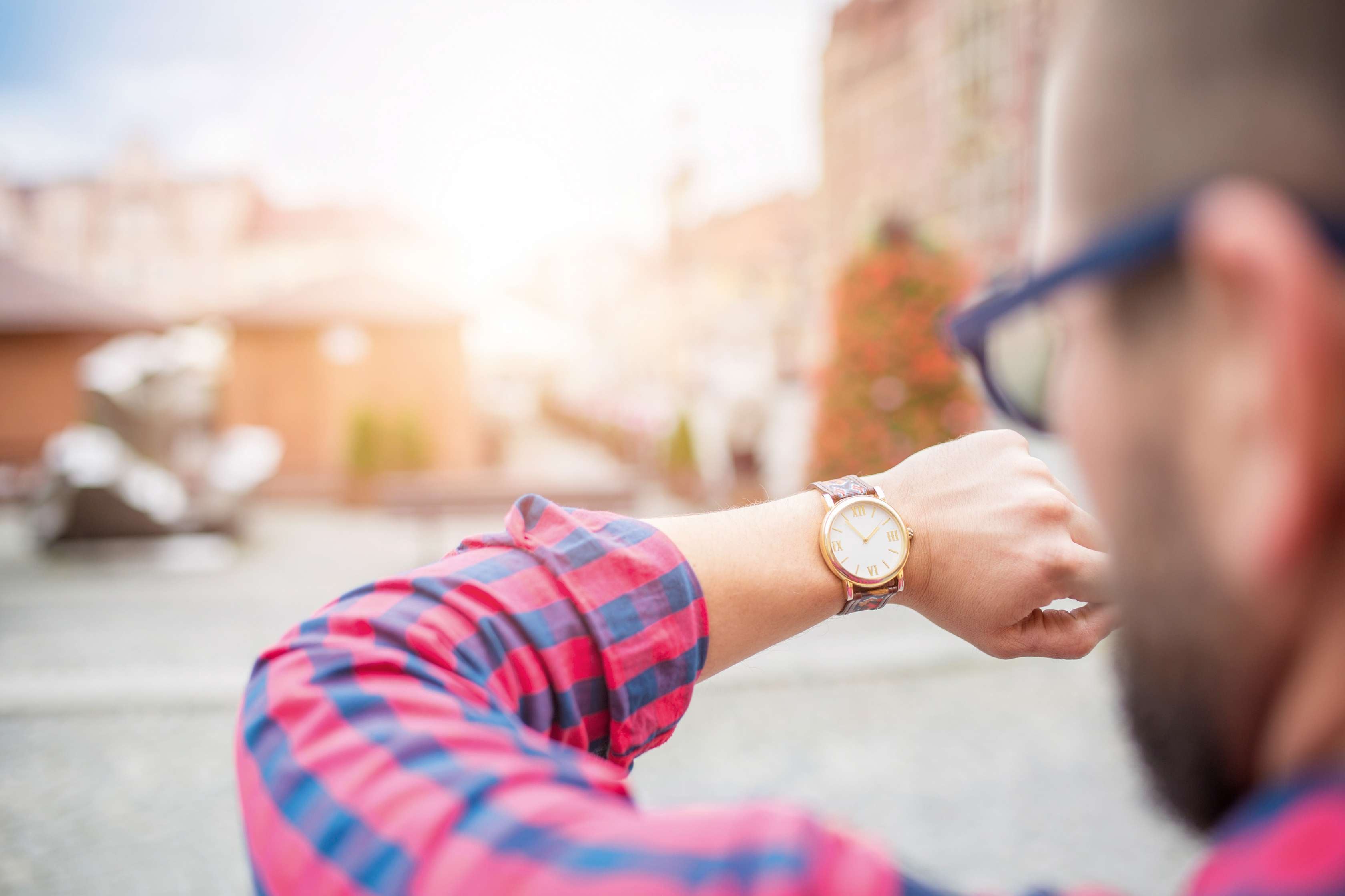 Allianz Gesundheitswelt - Stress-Test Online: Ein Mann mit Brille und karrieretem Hemd sieht auf seine Armbanduhr.