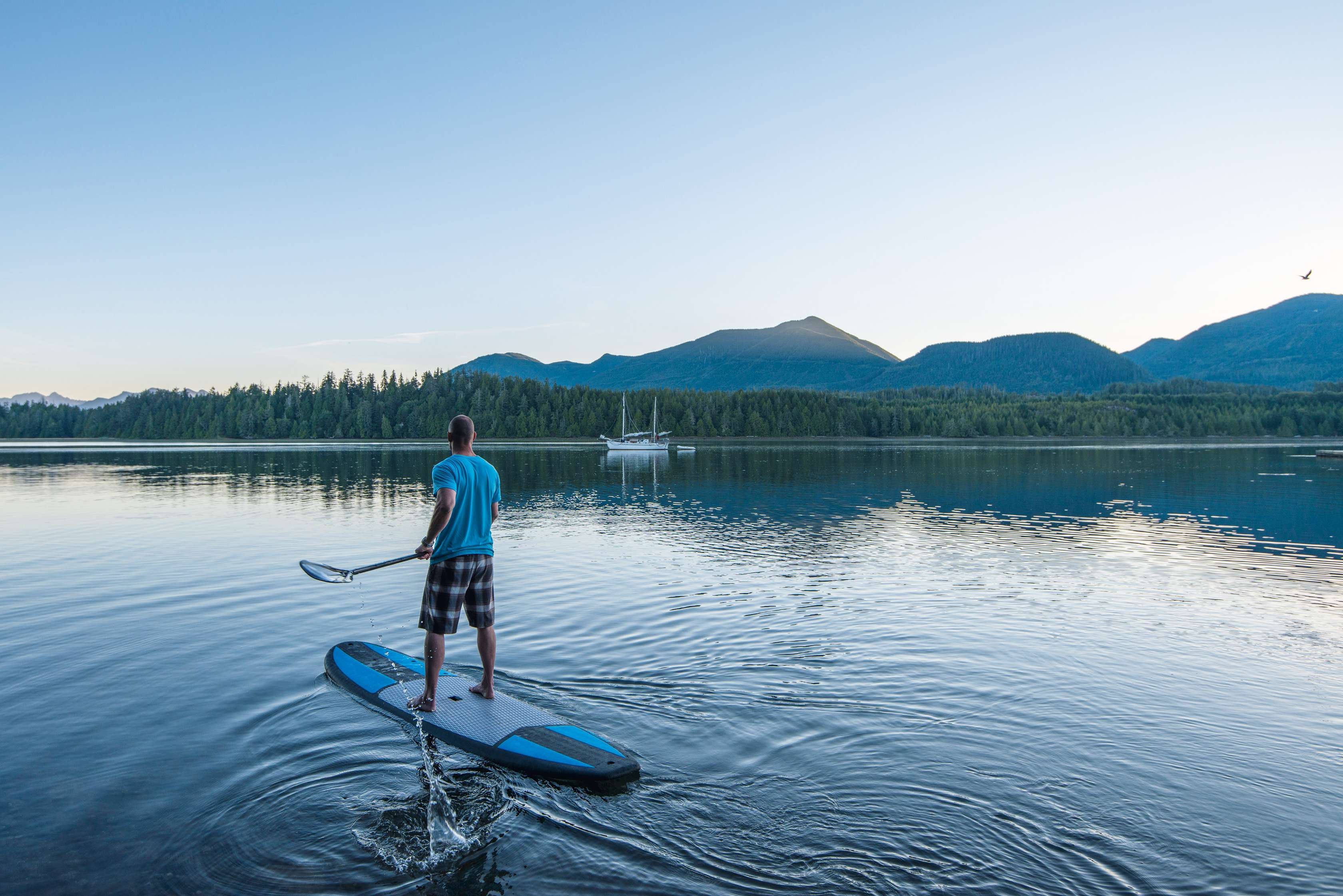 Allianz Gesundheitswelt - Stressmanagement im Alltag: ein Mann fährt auf einem blauen Standup Paddle vor dem Bergpanorama über den See.