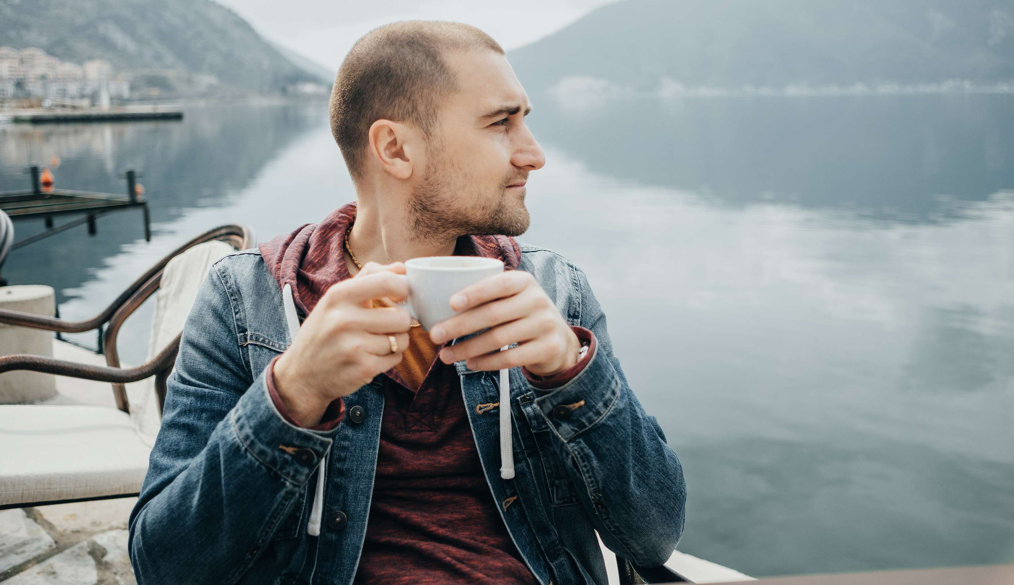 Allianz Gesundheitswelt - Männerkrankheiten und Vorsorge: ein junger mann sitzt mit einer Tasse am See und blickt in die Ferne.