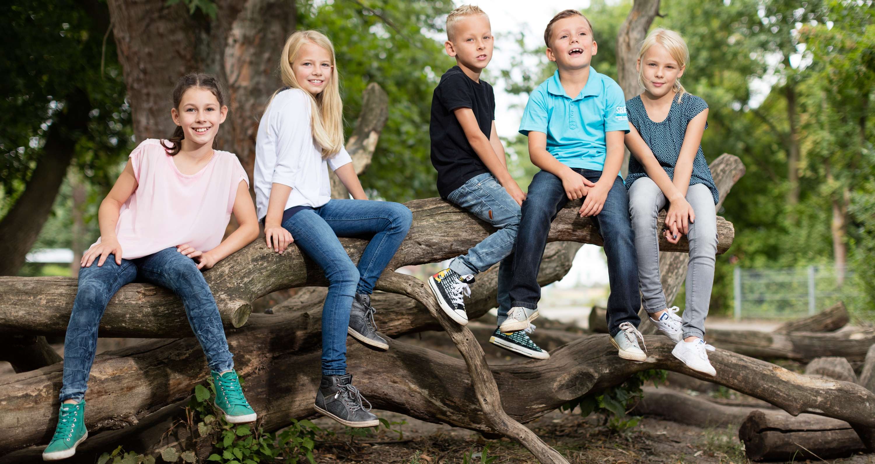 Allianz Gesundheitswelt - Mobbing bei Kindern: 3 Mädchen und 2 Jungen sitzen auf einem Baumstamm
