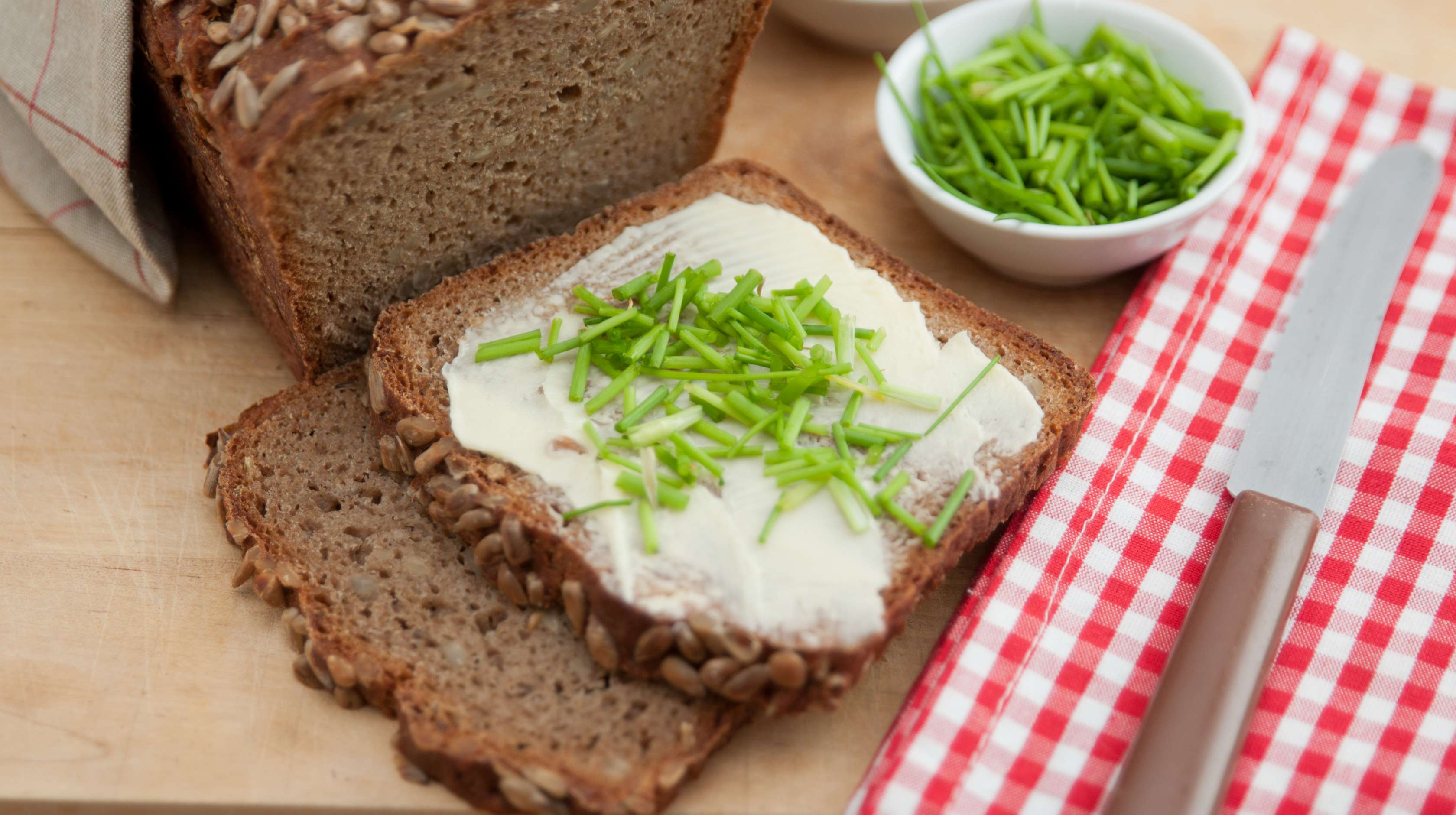 Allianz Gesundheitswelt - Ballasstoffe: eine Scheibe Vollkornbrot ist mit Butter beschmiert und mit Schnittlauch garniert.