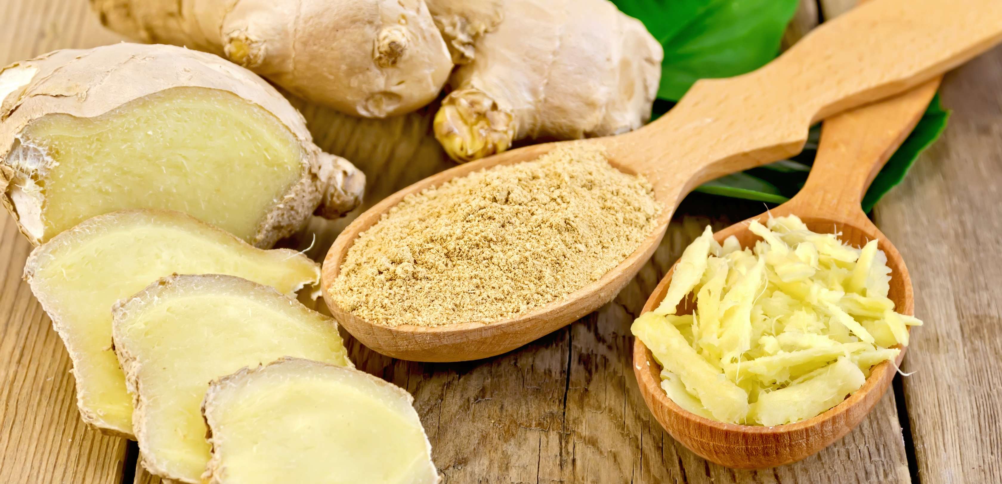 Allianz Gesundheitswelt - Ingwer: Ingwer in verschiedenen Arten - aufgeschnitten, in Pulverform, geraspelt und ganz - liegt auf einer Holzplatte.
