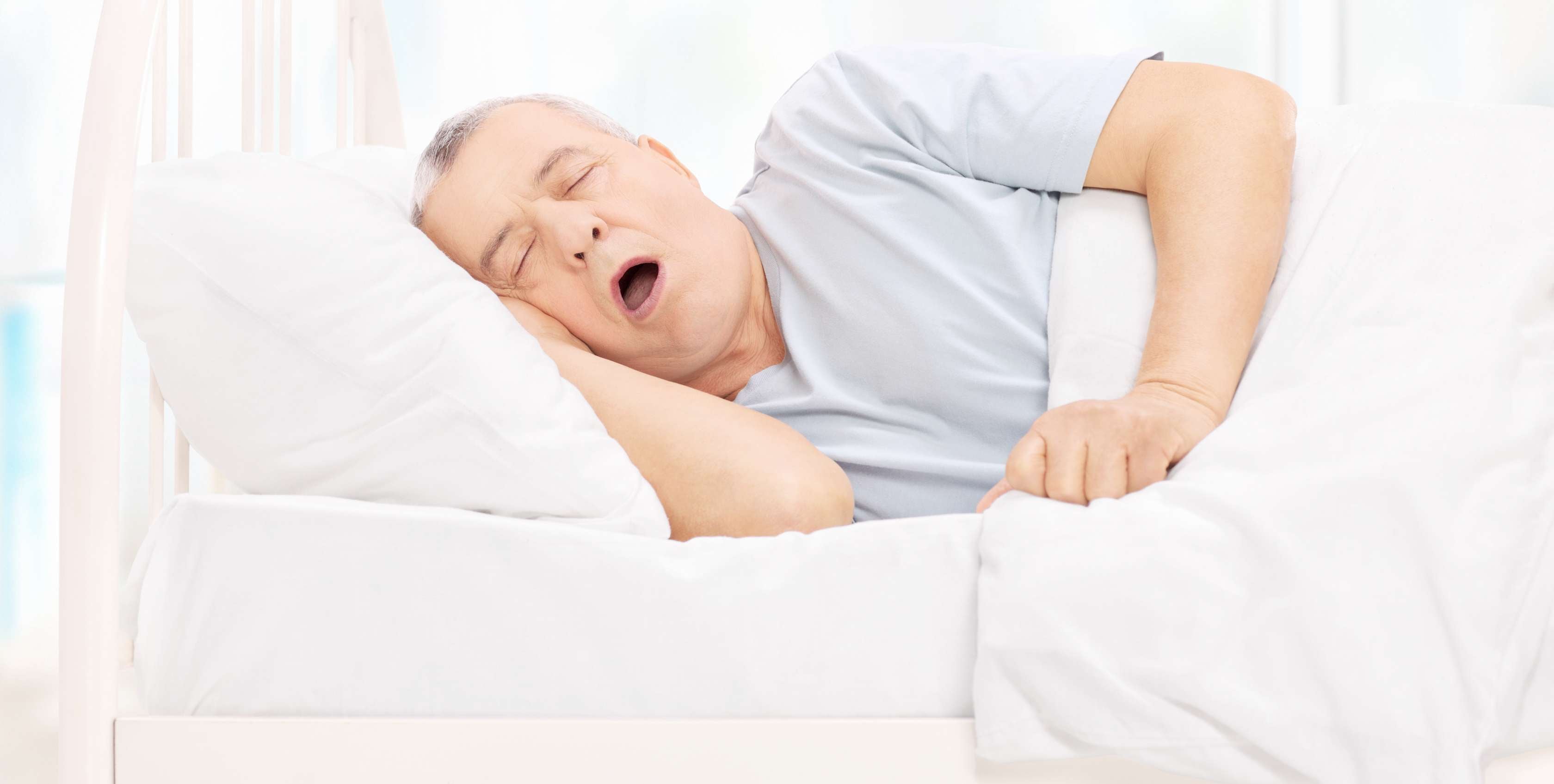 Allianz Gesundheitswelt - Schnarchen oder Schlafapnoe: Mann schläft mit offenem Mund im Bett