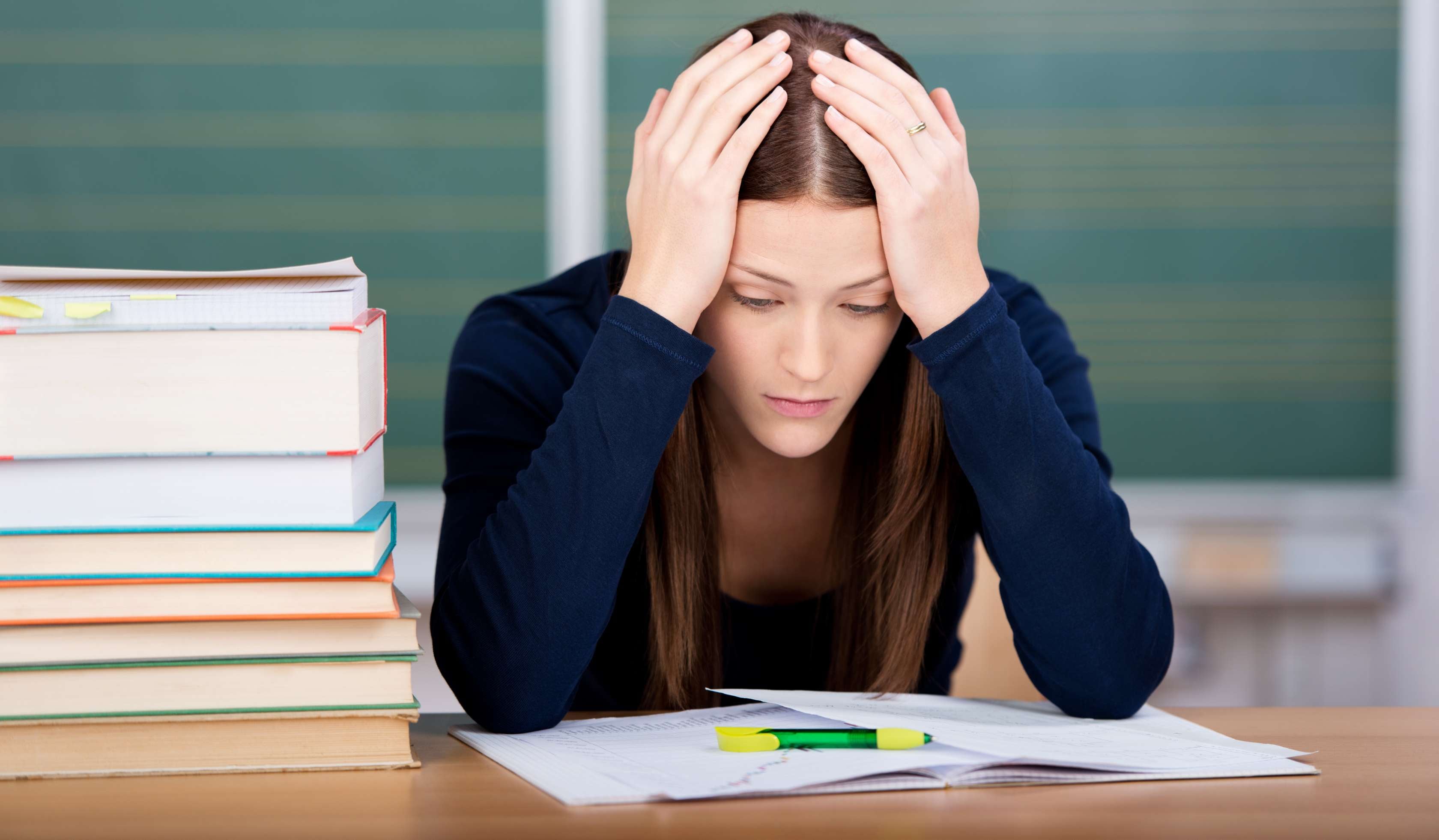Allianz Gesundheitswelt - Prüfungsangst: Mädchen sitzt mit über dem Kopf zusammengeschlagenen Armen vor einer Schulprüfung