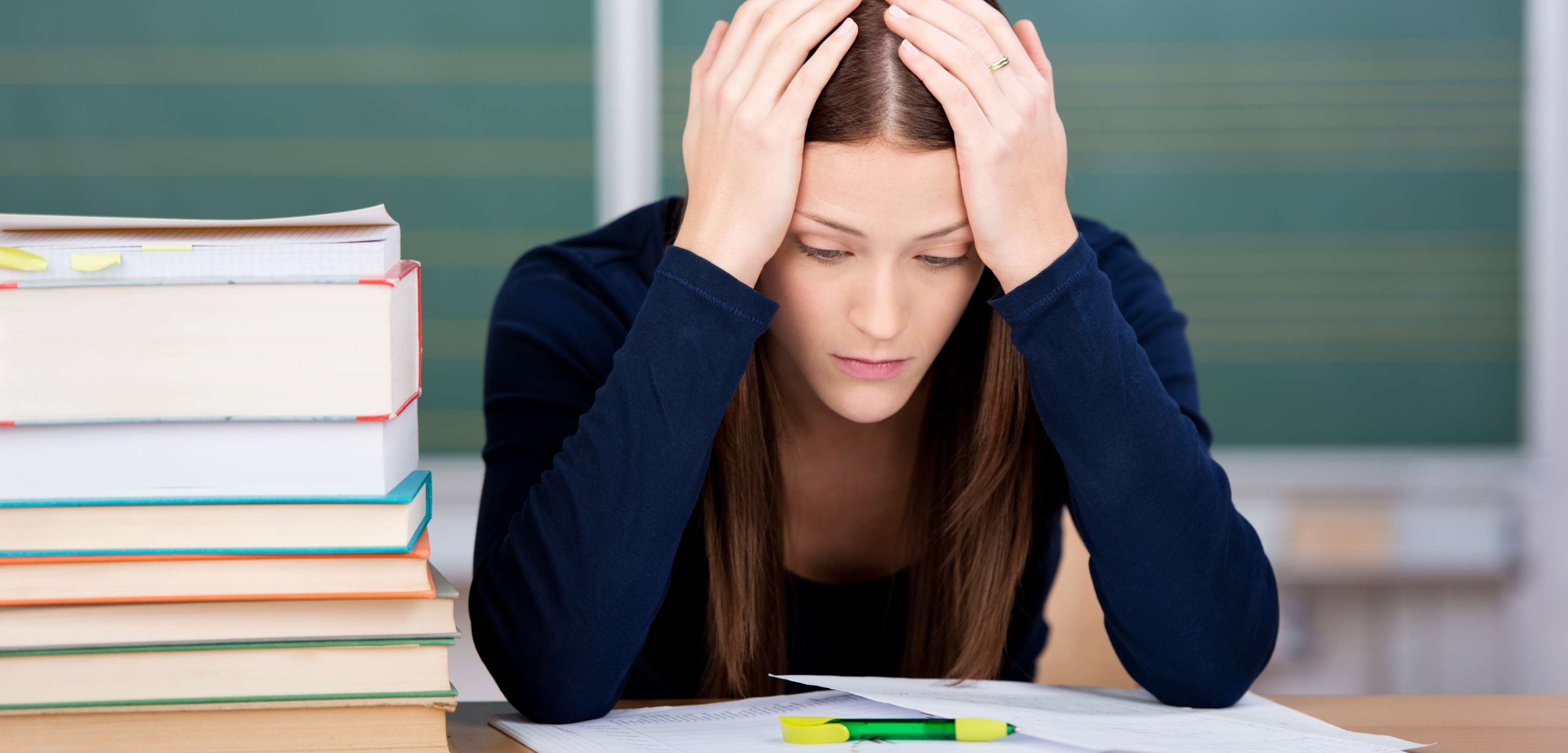 Allianz Gesundheitswelt - Prüfungsangst: Mädchen sitzt mit über dem Kopf zusammengeschlagenen Armen vor einer Schulprüfung