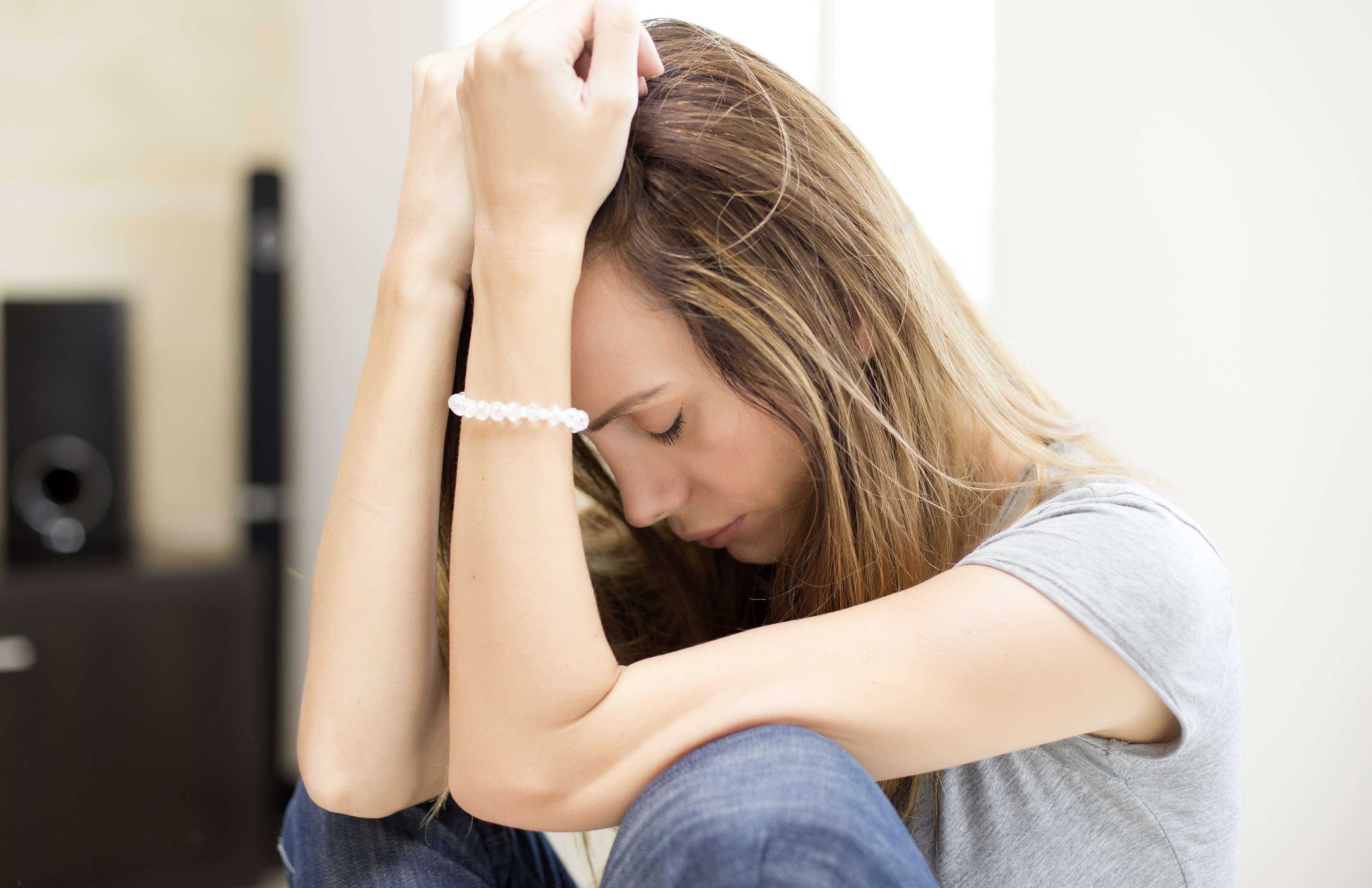 Allianz Gesundheitswelt - Trauer: Frau sitzt traurig auf dem Boden