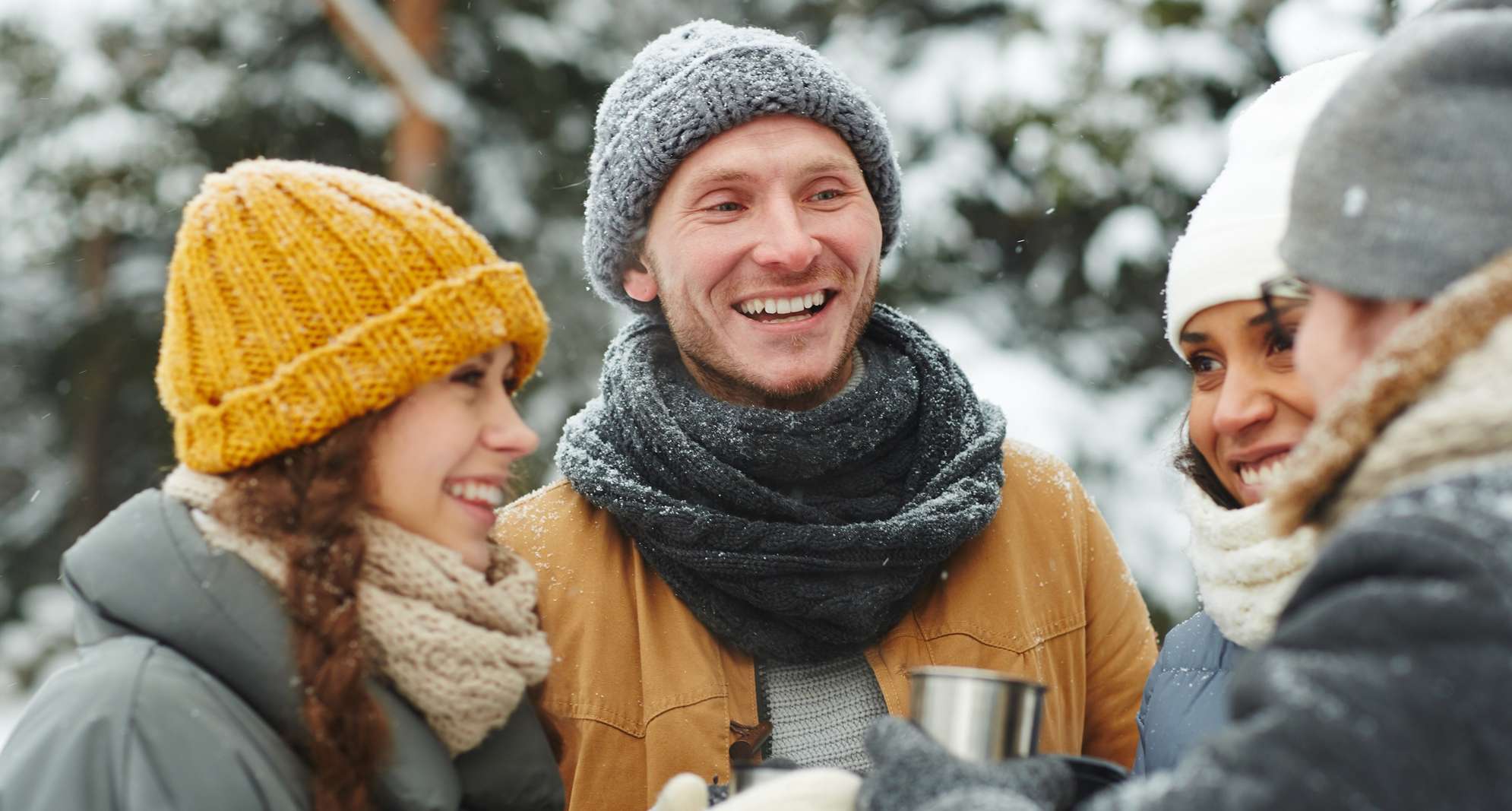 Allianz Gesundheitswelt - Winterdepression vorbeugen:Eine Gruppe junger Menschen steht lächelnd in einer Winterlandschaft