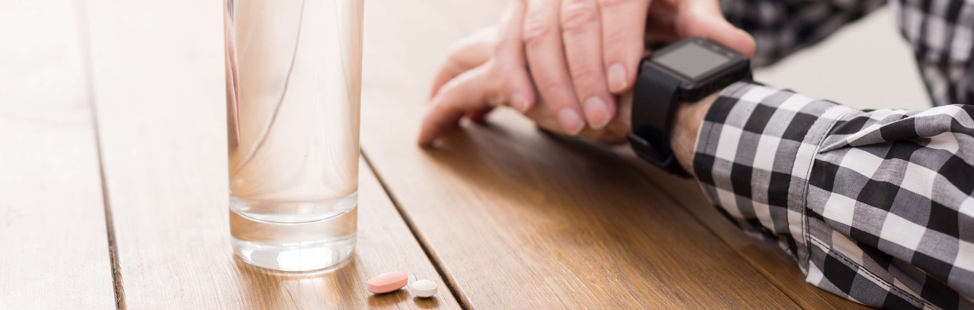 Allianz Gesundheitswelt - Säureblocker: Auf einem Tisch steht ein Glas Wasser mit zwei Tabletten, die Magensäure blocken und Übersäuerung des Körpers vorbeugen. 