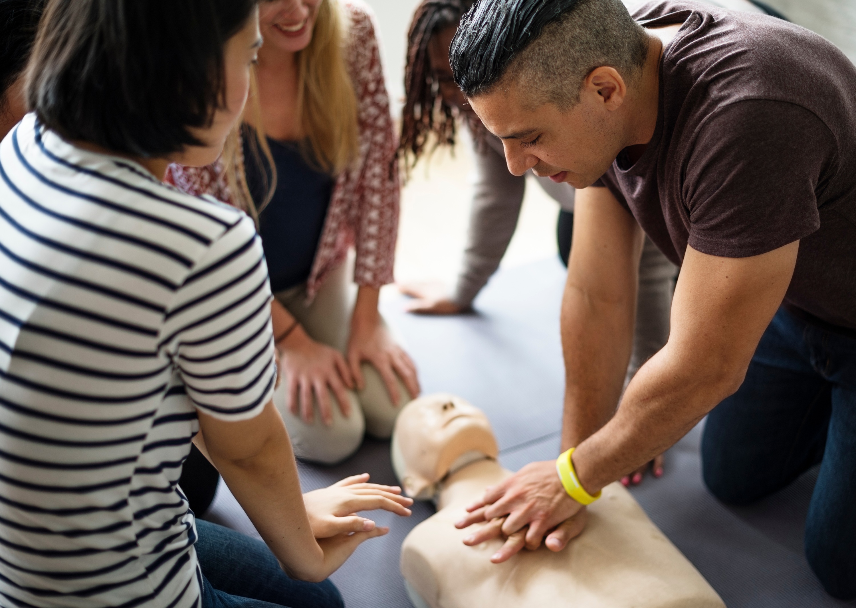 Mehrere Personen üben an einer Puppe die Herzdruckmassage in einem Erste-Hilfe-Kurs