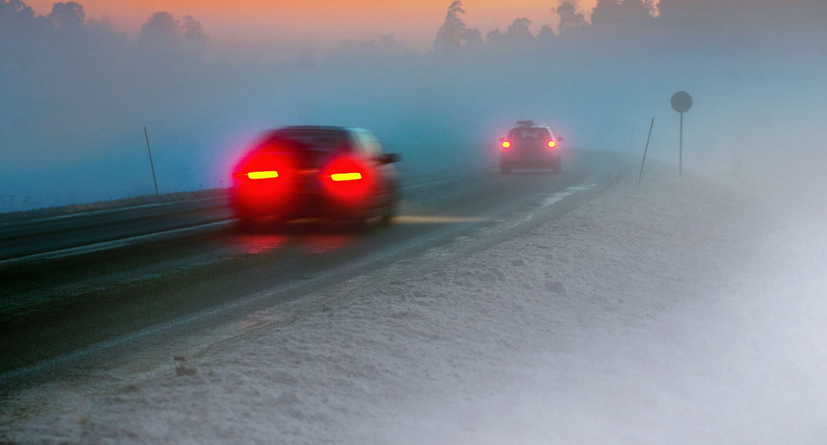Allianz Gesundheitswelt - Gefahren Herbst: Auf einer spätherbstlichen fahren zwei Autos in der Dämmerung durch den Nebel.