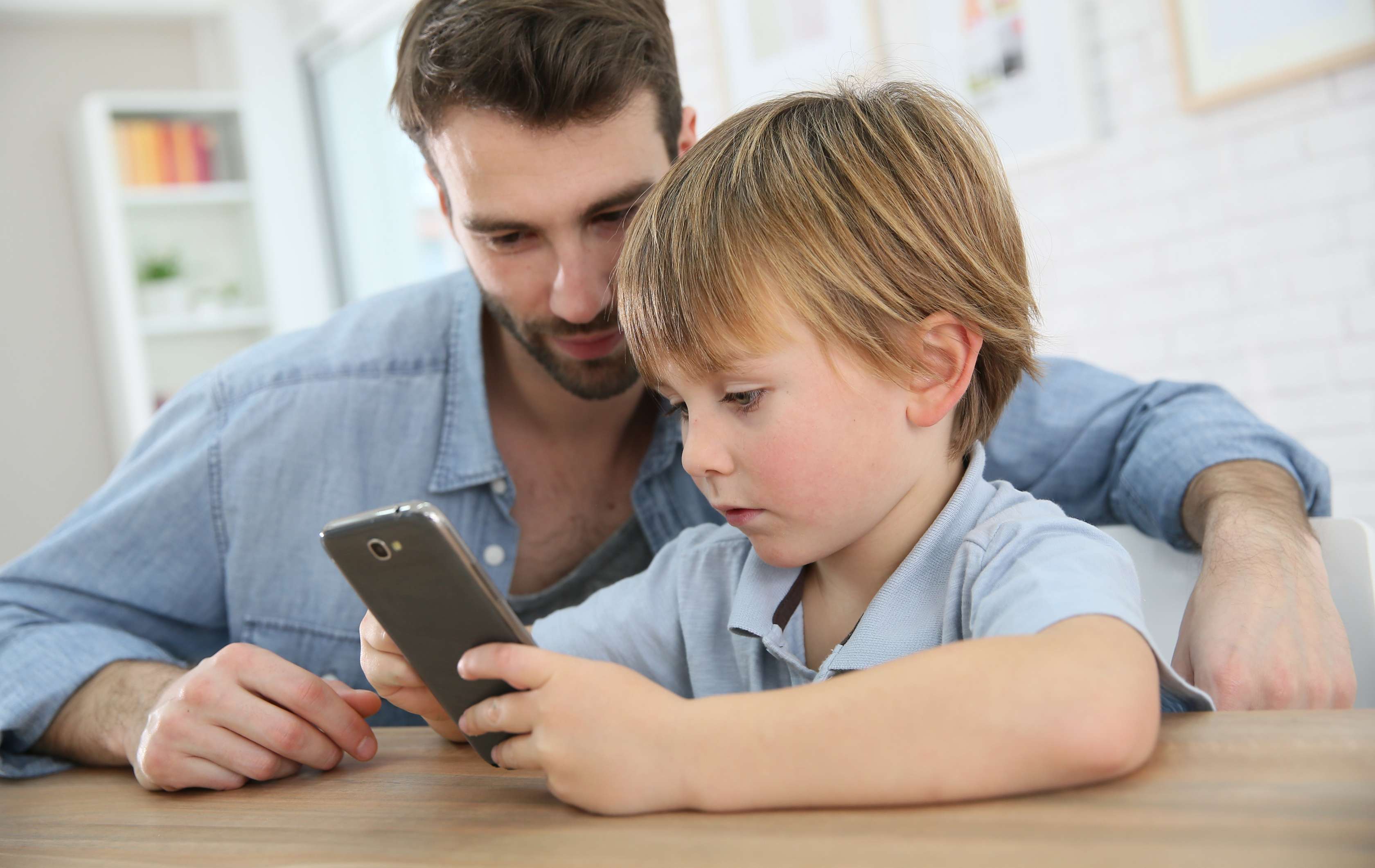 Allianz Gesundheitswelt - seriöse Gesundheit-Apps erkennen: ein Vater hilft seinem Sohn auf dem Smartphone sichere Gesundhetsapps zu erkennen.