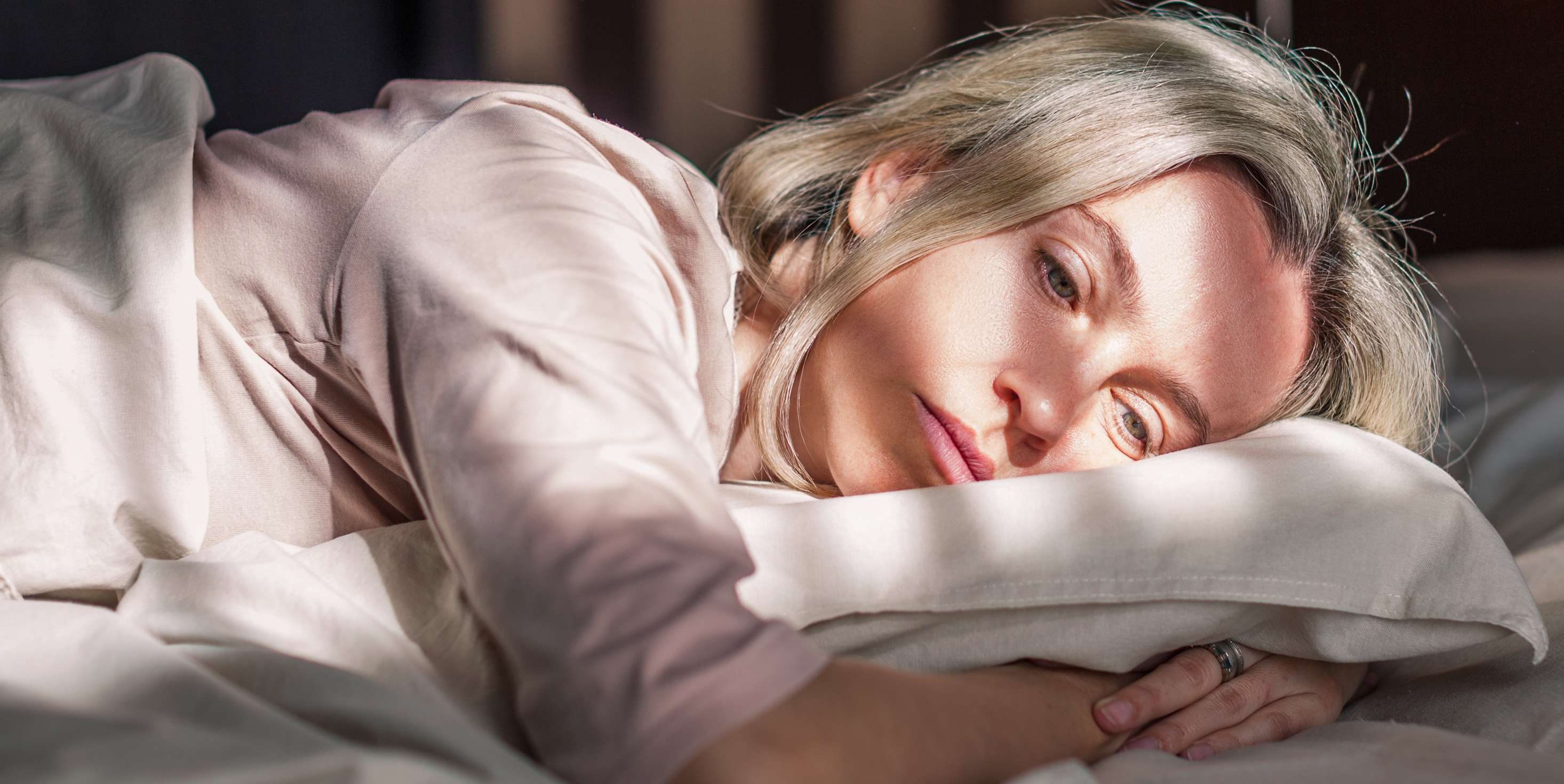 Allianz gesundheitswelt - Burnout vorbeugen: eine Frau liegt niedergeschlagen auf einem Bett