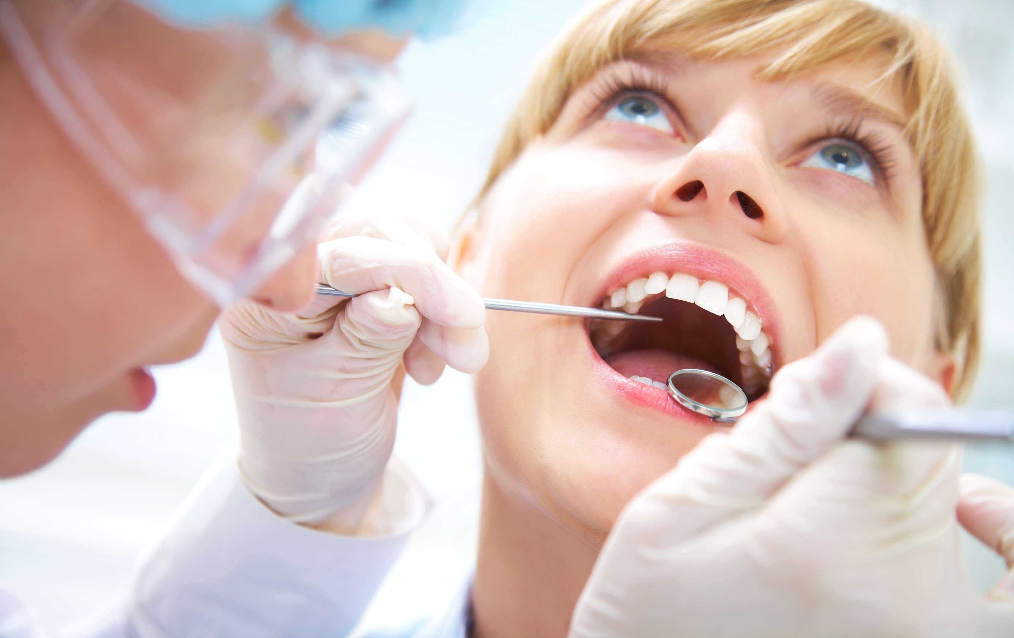 Allianz Gesundheitswelt - Zusammensetzung Zahnarztrechnung gesetzlich Versicherte: eine Frau wird von einer Zahnärztin untersucht. Die Zahnärztin hat einen Spiegel und ein ein spitzes Instrument in der Hand.