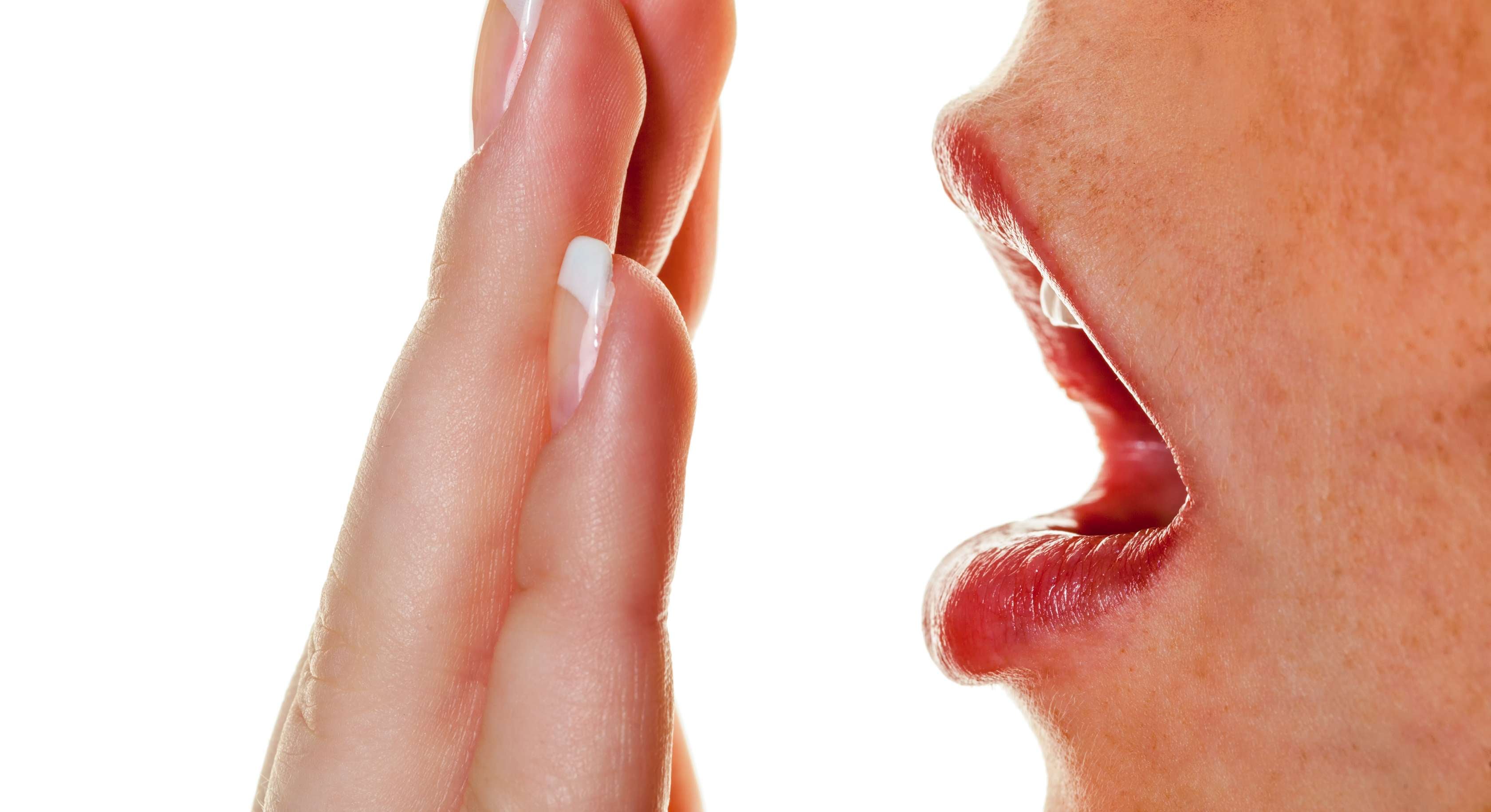 Allianz Gesundheitswelt - frischer Atem: eine Frau hält sich eine Hand vor den Mund und atmet dagegen, um ihren Atem zu prüfen.