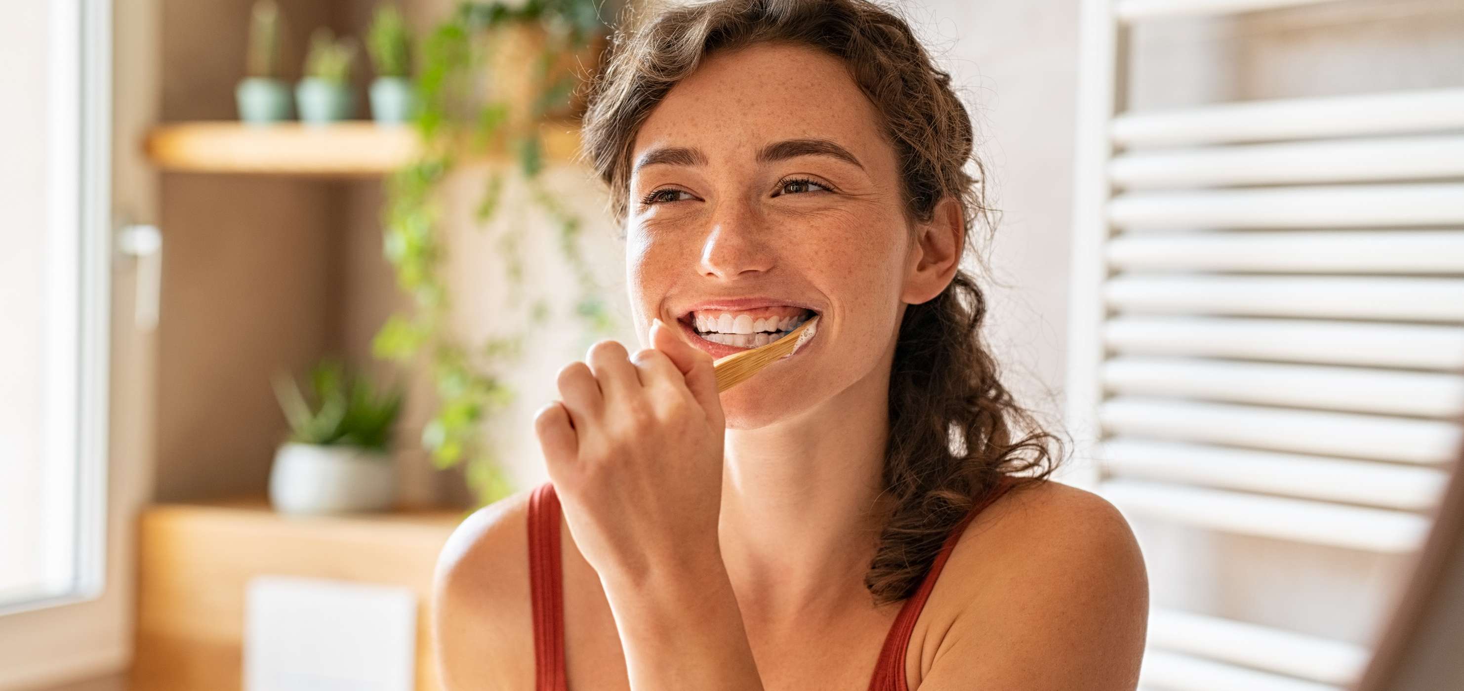 Allianz Gesundheitswelt -Zahnhygiene: Frau putzt sich lächelnd die Zähne