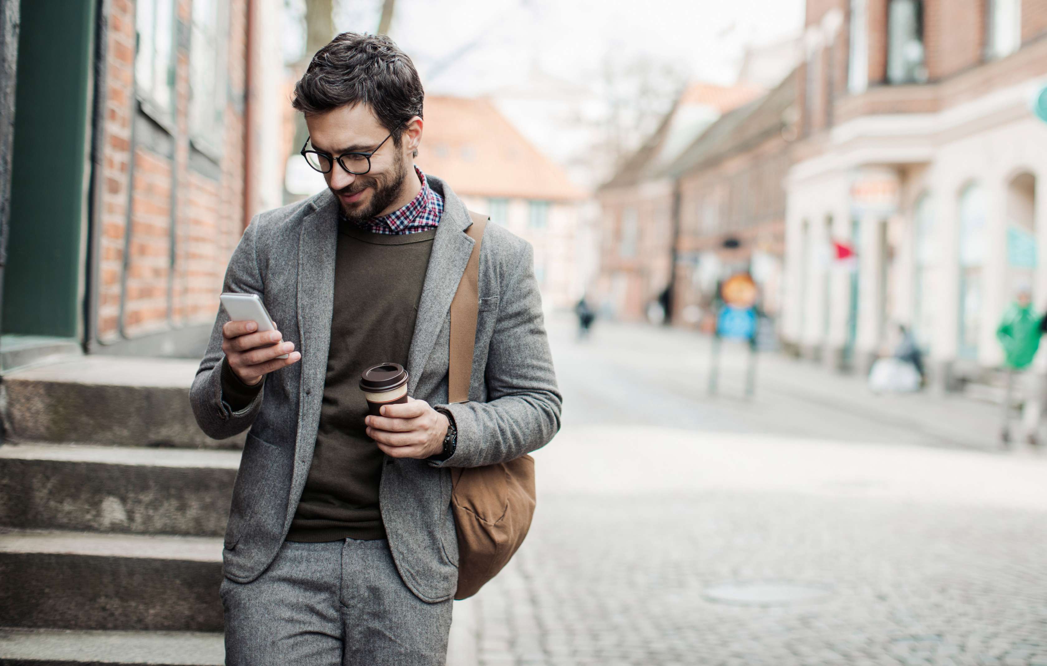 Allianz Gesundheitswelt - Kontakt: Mann läuft eine Straße entlang und blickt auf sein Smartphone
