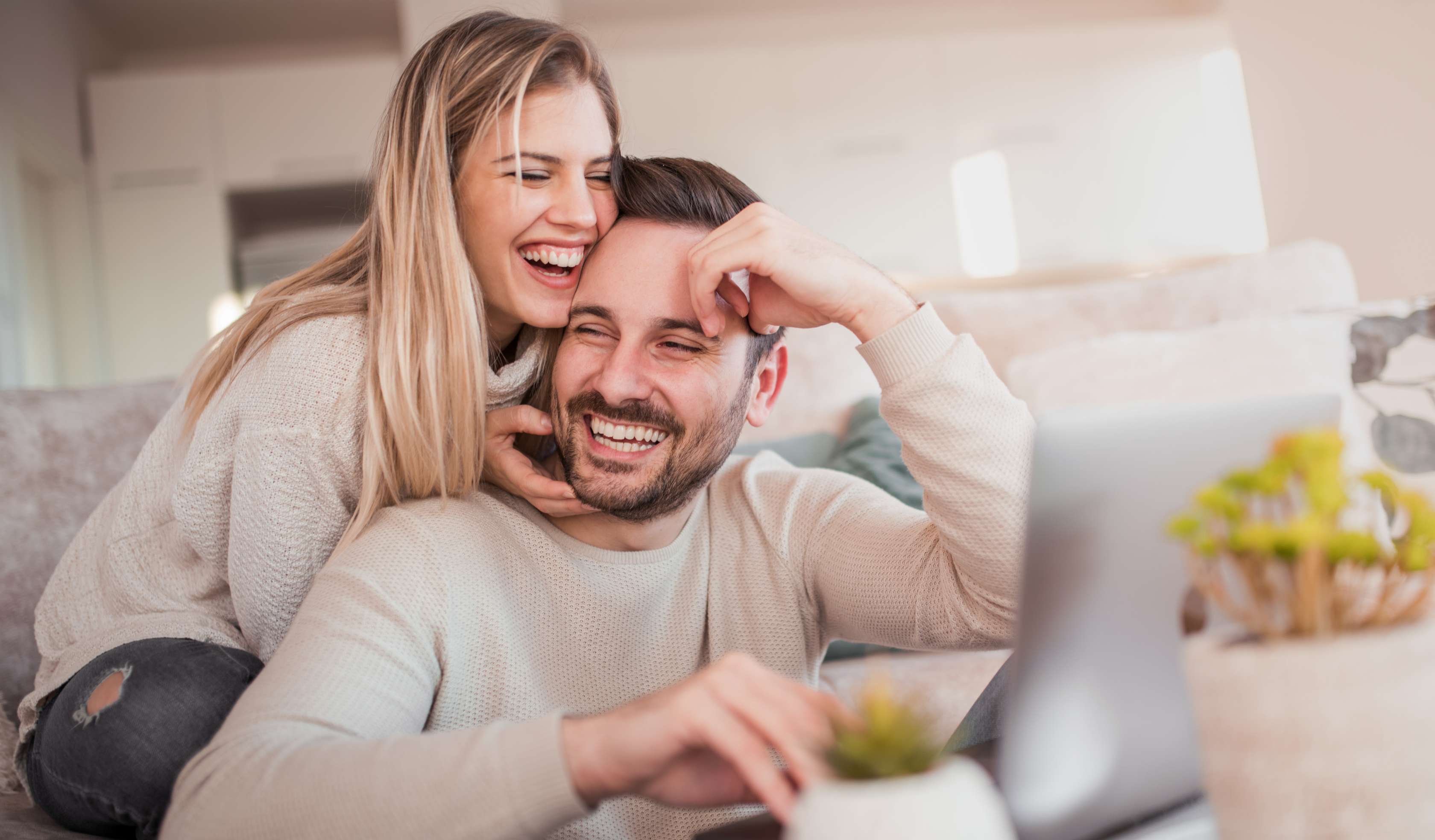 Allianz Gesundheitswelt - Privatversichert: Mann und Frau sitzen lachend auf einer Couch