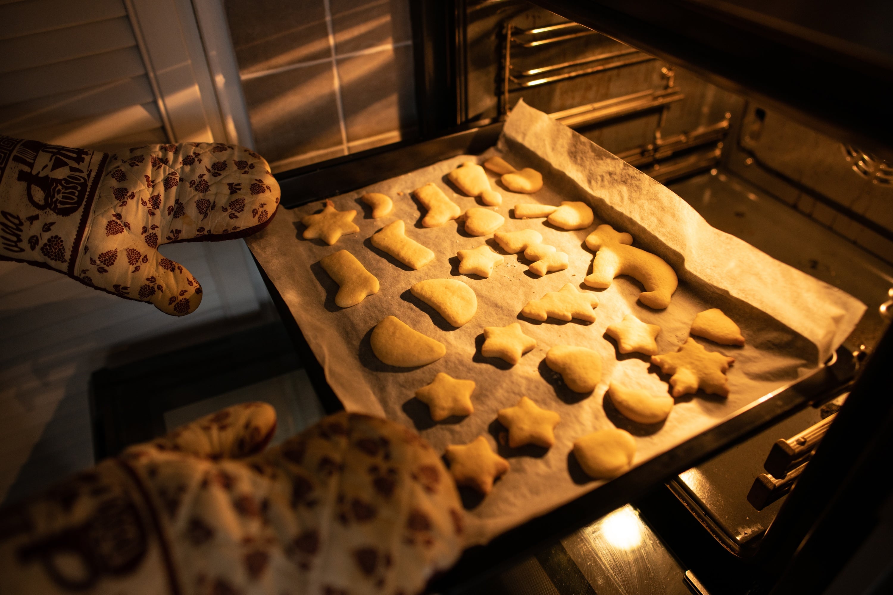 Ein Backblech mit Plätzchen wird aus dem Backrohr herausgeholt