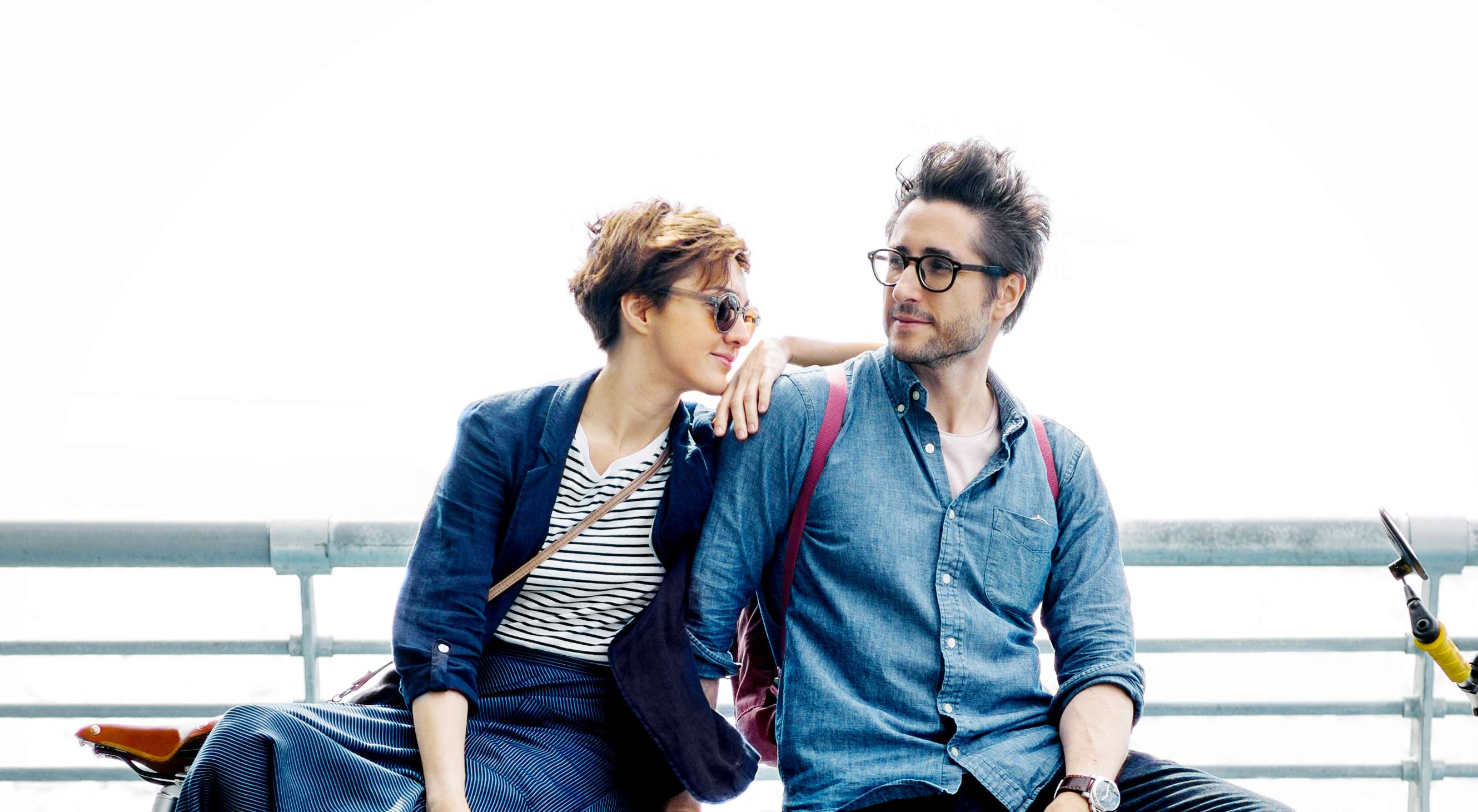 Allianz Gesundheitswelt - Gesundheitsservices: eineunges Paar mit Fahrrädern sitzt aneinandergelehnt auf einer Mauer.