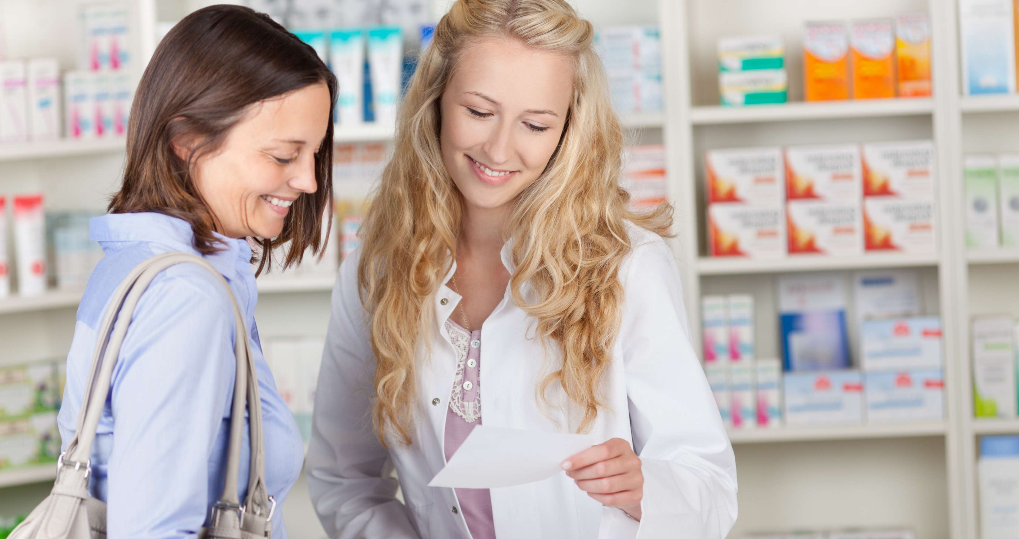 Allianz Gesundheitswelt - Arzneimittelservice Apotheken: eine junge Frau mit dunklen Haaren wird von einer Apothekerin mit langen blonden Haaren beraten.