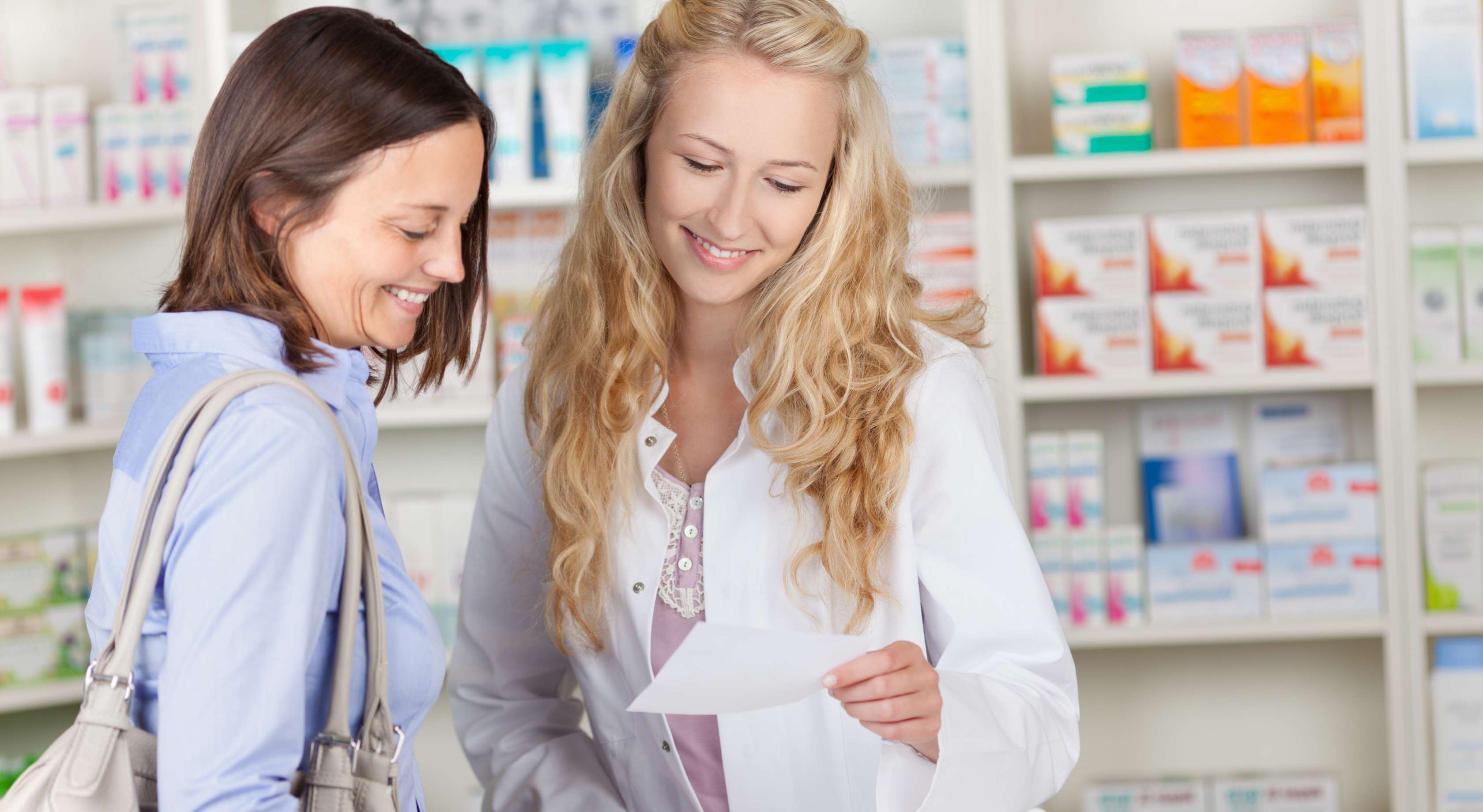 Allianz Gesundheitswelt - Arzneimittelservice Versandapotheken: eine junge Frau mit dunklen Haaren wird von einer Apothekerin mit langen blonden Haaren beraten.