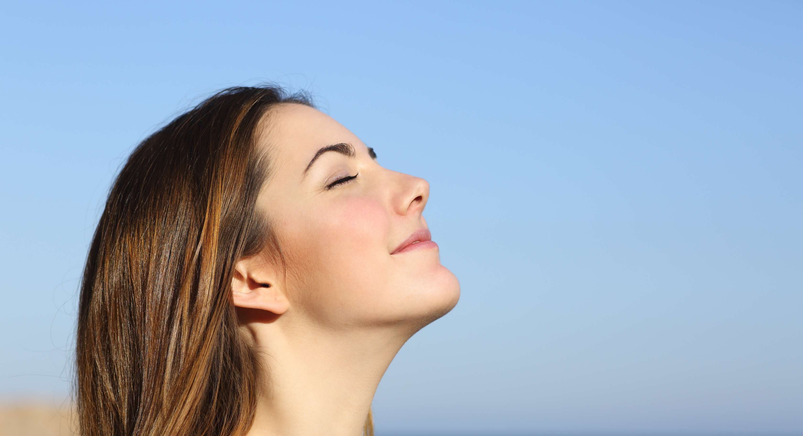 Allianz Gesundheitswelt - mein AtemwegsCoach: eine junge Frau steht am Meer und atmet tief durch.