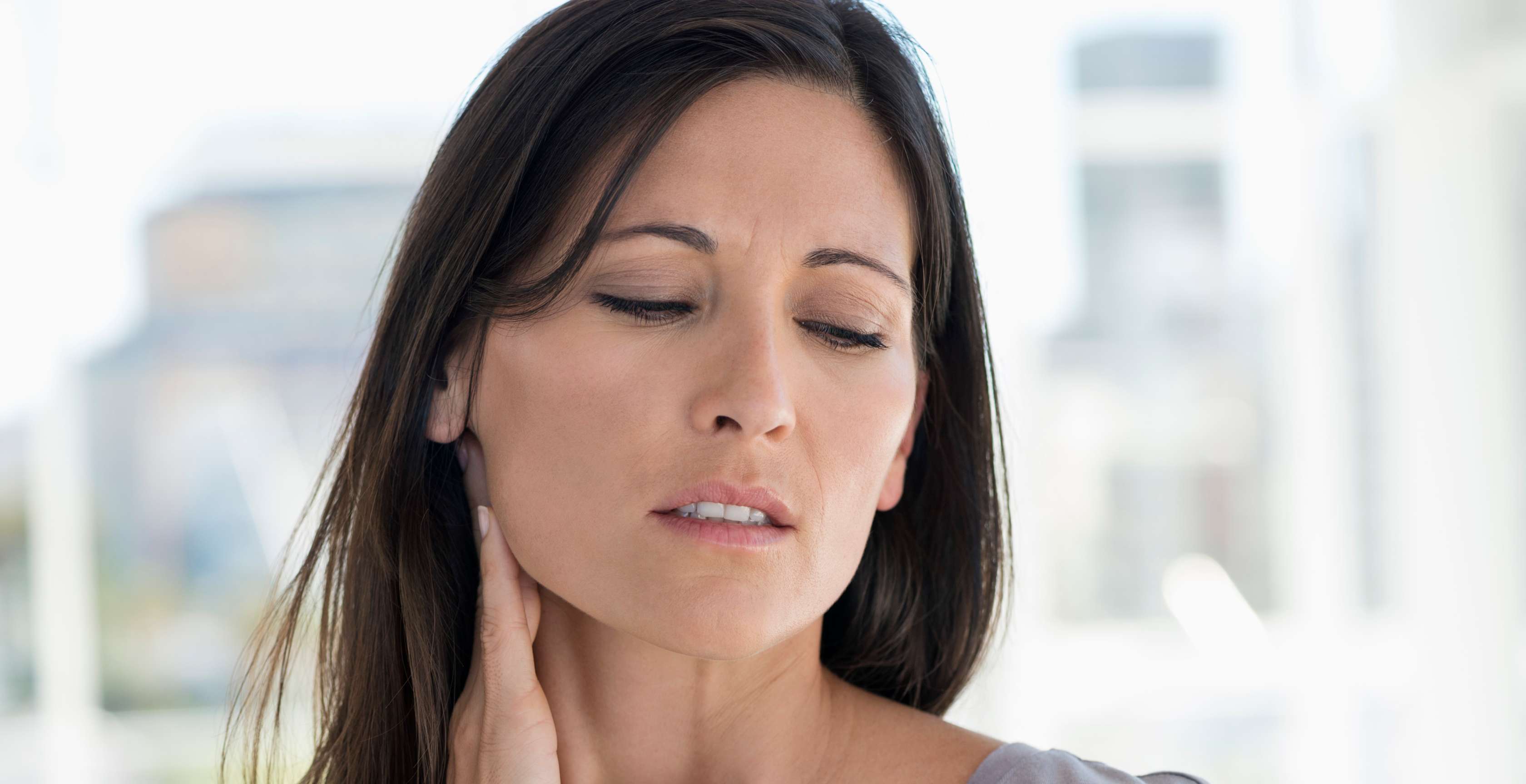 Allianz Gesundheitswelt - Mein SchmerzCoach: Eine Frau mit langen dunklen Haaren hält sich den schmerzenden Nacken.