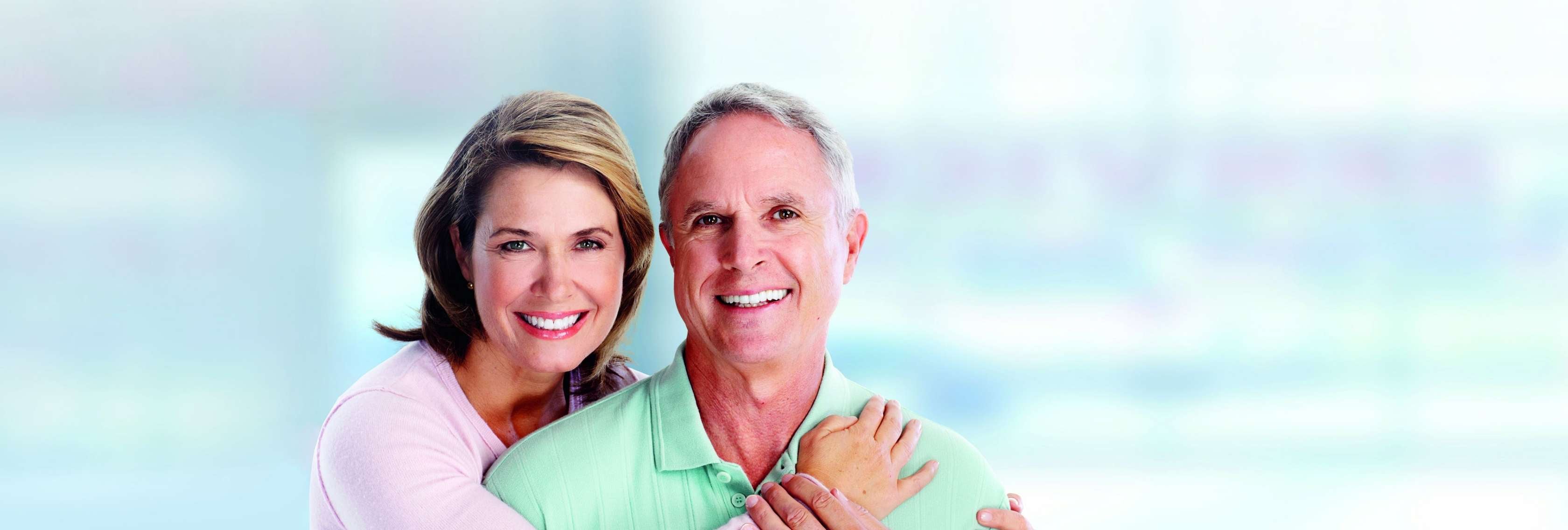 Allianz Gesundheitswelt - Allianz Spezialisten Vermittlung: ein älteres Ehepaar lacht in die Kamera. Der Mann wird von der Frau von hinten umarmt.